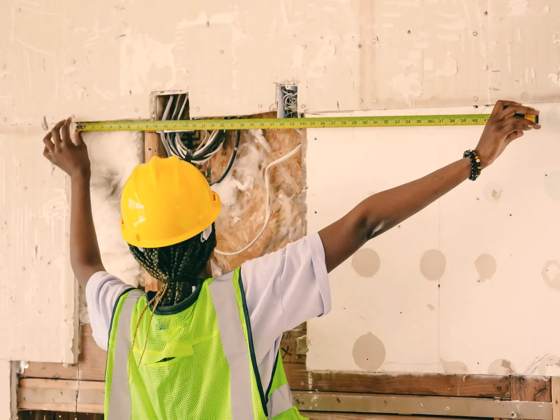 A remodeler measures an opening in a kitchen under renovation.